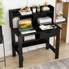 A black desk with a laptop, books, and office supplies on it, set against a white wall and a bookshelf. Produktbild-Vorschau