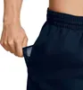 A close-up shot of a person's hand reaching into the pocket of navy blue shorts. Podgląd zdjęcia produktu