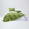 A neatly made bed with green striped bedding and pillows on a white background. Náhled obrázku produktu