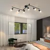A bedroom with a track light fixture, sheer curtains, a green armchair, and a bed. Podgląd zdjęcia produktu