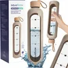 A collage of images showcasing a glass water bottle with a motivational design and a silicone sleeve, along with its packaging. Produktbild-Vorschau