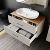 A modern bathroom vanity with a sink and storage drawers, set against a dark tiled wall and wooden floor. Produktbild-Vorschau