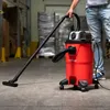 A person is using a red industrial vacuum cleaner in a warehouse or workshop setting. Náhľad obrázku produktu