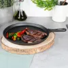 A cast iron crepe pan with two steaks and vegetables on a wooden board. Voir les images du produit