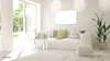 A bright, modern living room with a white sofa, a coffee table with decorative items, and a large window overlooking a garden. Podgląd zdjęcia produktu