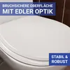 A close-up view of a white toilet seat with text overlays highlighting its features. Produktbild-Vorschau