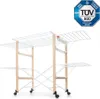 A multi-tiered clothes drying rack with wooden supports and white metal drying rods, shown on a white background. A TÜV SÜD certification logo is visible in the top right corner. Podgląd zdjęcia produktu