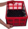 Hands holding a red and black foldable storage crate. Produktbild-Vorschau