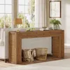 A wooden console table is placed behind a sofa, next to a window with curtains. Decorative items like a lamp, books, and a plant are on the table, and baskets are placed underneath. Anteprima dell’immagine prodotto