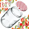 A clear glass jar with a red and white checkered lid is shown, surrounded by various fresh vegetables and herbs, with a stylized letter 'K' logo in the upper left corner. Produktbild-Vorschau