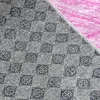 A close-up view of a textured fabric with a checkered pattern in gray and a pink fabric in the background. Náhled obrázku produktu