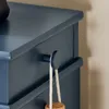 A close-up view of a blue cabinet with a round knob and a rope hanging from it. Produktbild-Vorschau