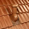 A close-up view of a brown roof vent installed on a tiled roof. Produktbild-Vorschau