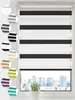 A close-up view of a black and white striped roller blind in a window, with a cityscape visible outside.