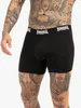 A close-up view of a man wearing black Lonsdale boxer shorts, with tattoos visible on his torso and legs. Produktbild-Vorschau