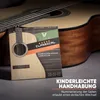 A package of guitar strings is placed in front of a guitar. Náhled obrázku produktu