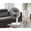 A white desk fan is placed on a glass table in a living room with a black leather sofa in the background. Anteprima dell’immagine prodotto