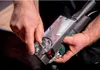 A person's hands are holding and adjusting a power tool. Anteprima dell’immagine prodotto