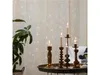 A table with candles and a plant in front of a curtain with fairy lights. Produktbild-Vorschau
