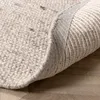 A close-up view of a round rug, showing its textured surface and the underside where it is rolled up. Produktbild-Vorschau