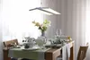 A dining table set for a meal, with a modern LED pendant light hanging above. Produktbild-Vorschau