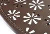 A close-up view of a brown metal garden table with a decorative floral cut-out pattern and a twisted metal trim along the edge. Produktbild-Vorschau