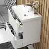 A white bathroom vanity with a sink and drawers, featuring cosmetic products and a roll of toilet paper. The background includes patterned tiles and vertical wooden slats. Produktbild-Vorschau