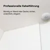 A white cable channel is installed along the corner of a ceiling and wall, with a small white device attached to the ceiling. Produktbild-Vorschau