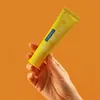 A hand holding a tube of toothpaste against an orange background. Anteprima dell’immagine prodotto