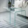 Two nesting glass tables are placed on a tiled floor next to a white sofa with a blanket draped over it. A potted plant and a glass of water with mint are on the larger table. Podgląd zdjęcia produktu