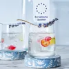Two glasses of sparkling water with fruit and lavender garnishes, placed on decorative coasters. Produktbild-Vorschau