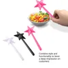 A hand holding a pink star-shaped wand over a bowl of salad, with three star-shaped wands in pink, black, and white arranged in the foreground. Náhľad obrázku produktu