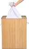 A hand is placing a white laundry bag into a bamboo laundry basket. Produktbild-Vorschau