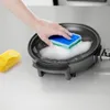 A hand is cleaning an electric frying pan with a sponge and soap. Produktbild-Vorschau