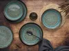 A top-down view of a rustic table setting with multiple plates and a spoon. Produktbild-Vorschau