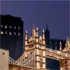 A detailed wooden model of the Tower Bridge at night, with lights illuminating parts of the structure and background buildings. Anteprima dell’immagine prodotto