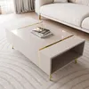 A modern living room setting with a beige coffee table and a white sofa. Produktbild-Vorschau