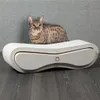 A cat is sitting on a modern, white and gray cat scratching post. Produktbild-Vorschau