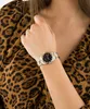 A woman wearing a leopard print top and a watch on her wrist. Produktbild-Vorschau