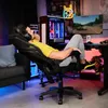 A man is relaxing in a gaming chair in front of a computer setup. Produktbild-Vorschau