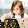 A young girl is playing with a colorful marble board game. Produktbild-Vorschau