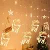 Christmas lights with reindeer and star shapes hanging indoors, with a Christmas tree in the background. Produktbild-Vorschau