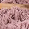 A close-up view of a fluffy pink rug with a wooden surface in the background. Produktbild-Vorschau