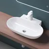 A white ceramic sink with a modern faucet is mounted on a wooden countertop against a teal wall. Produktbild-Vorschau