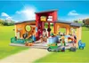 A Playmobil animal hotel playset set up in an outdoor grassy area with a blue sky and sun. Produktbild-Vorschau