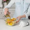 A person is adding ingredients to a bowl of spiralized vegetables. Produktbild-Vorschau
