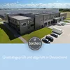 An aerial view of a modern industrial building with a logo and text overlay. Produktbild-Vorschau