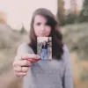 A woman holds a small photo of herself in front of her. Náhled obrázku produktu