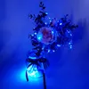 A bouquet of artificial flowers in a glass jar decorated with blue LED string lights. Produktbild-Vorschau