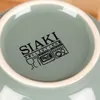 The underside of a green ceramic bowl with brand and care instructions printed on it. Produktbild-Vorschau